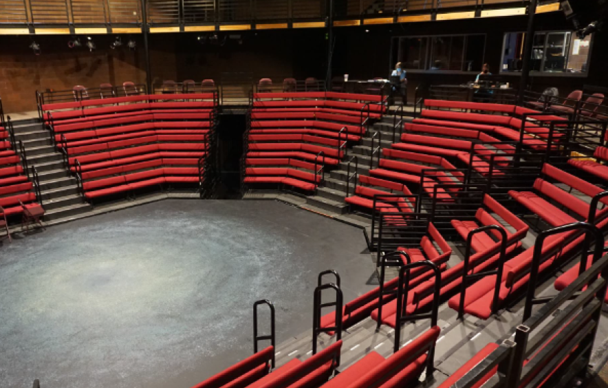empty black box theatre with rows of red seats