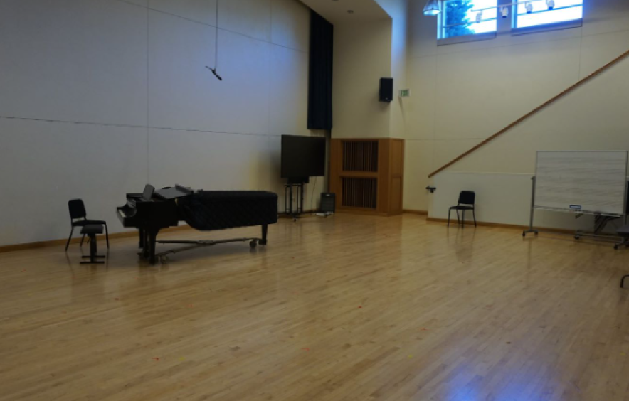 dimly lit wood floored rehearsal space with piano