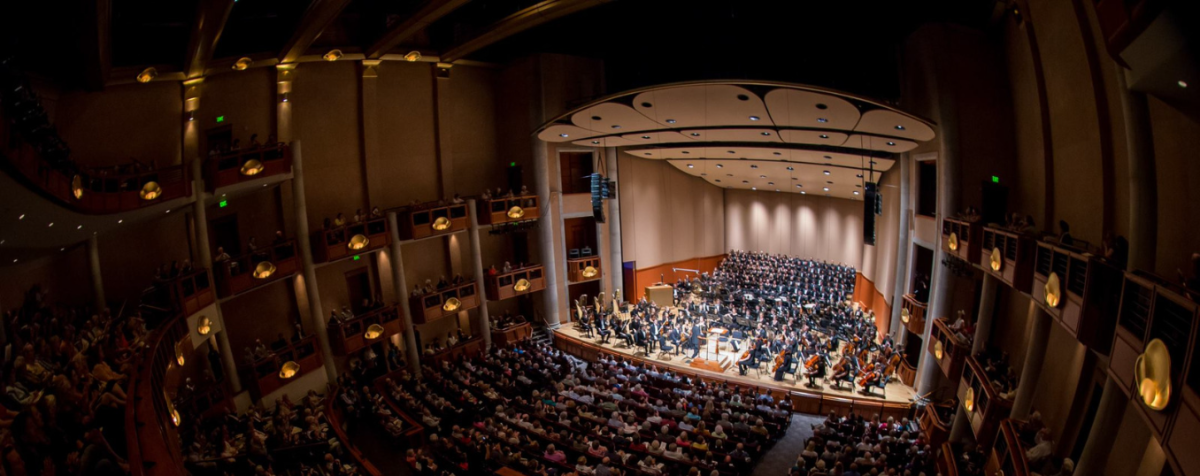 orchestra performing to grand, crowded concert hall