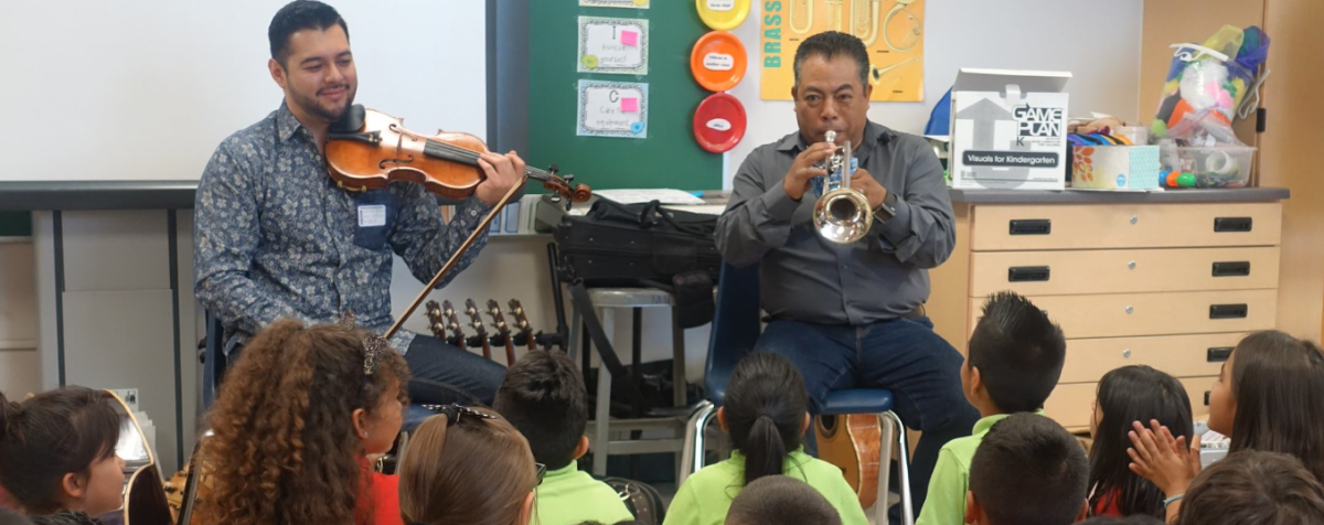 violinist and trumpeter playing in classroom to small children