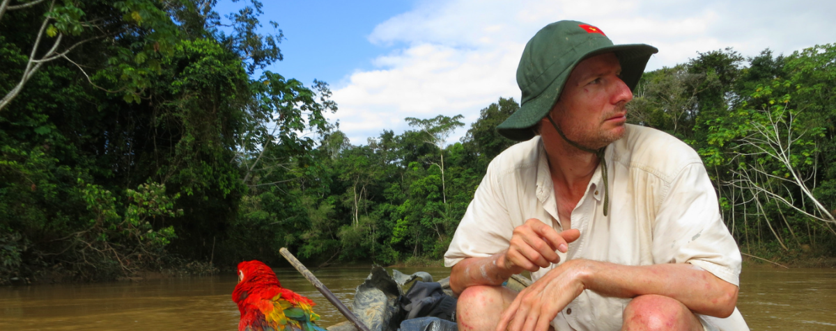 man in boat on river with parrot
